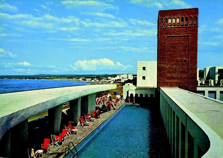 Après l’indépendance algérienne, Fernand Pouillon fut rappelé par le nouveau gouvernement pour concevoir et construire des complexes hôteliers. Pour l’hôtel El-Riadh de Siddi Ferruch à 30 km d’Alger, Fernand Pouillon crée un mix entre le style moderne international avec l’arrondi de la piscine et l’esprit traditionnel marocain de la tour en briques. Hôtel El-Riadh, Siddi Ferruch en Algérie.1966-1968.