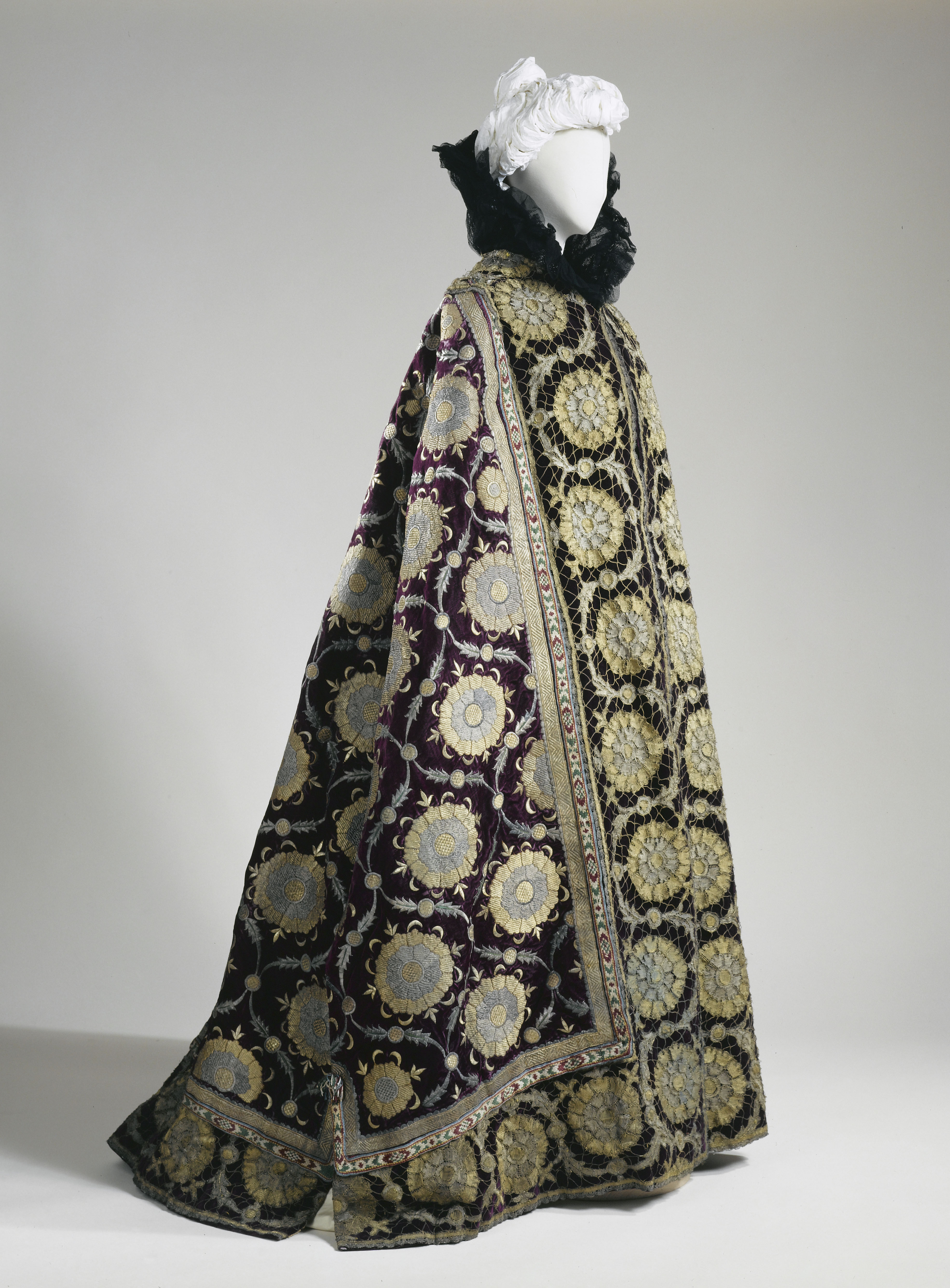 Charles-Frédric Worth Cape du soir de la comtesse Gref - fulhe , née Élisabeth de Caraman- Chimay (1860-1952), coupée dans un caftan de Boukhara offert par le tsar, vers 1896. Tissu façonné de soie et de filés mé - talliques à motifs de rosaces argent et or sur fond violet, mousseline noire, dentelle métallique or. © Patrick Pierrain / Galliera / Roger-Viollet