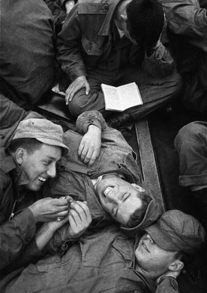 © Harold Feinstein, Soldiers lying on the deck of a crowded US military troopship to Korea pass the time talking and laughing while another reads, Unspecified location, 1952, © Harold Feinstein